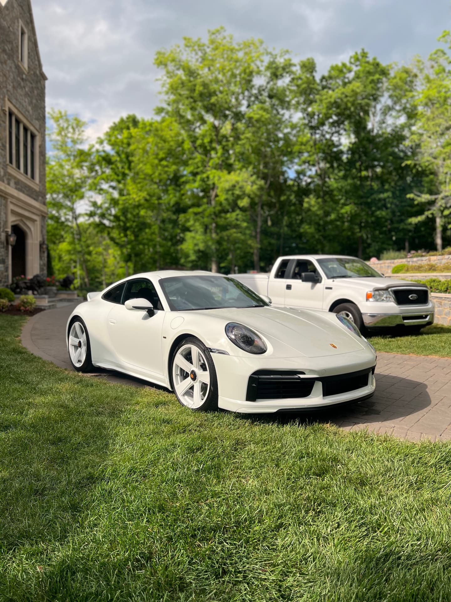 White Porsche 911 detailed to a mirror finish on a paver driveway